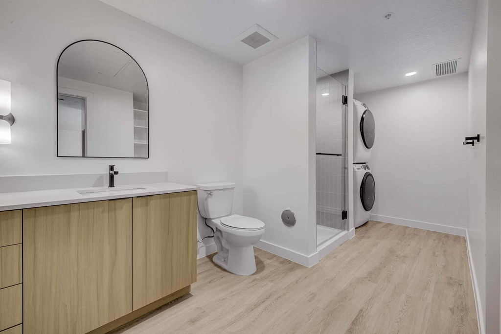 A bathroom with a toilet, sink, and mirror.