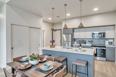 A modern kitchen with a dining table set for two.