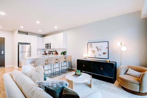 A modern living room with a white sofa, a black cabinet, and a dining table with chairs.