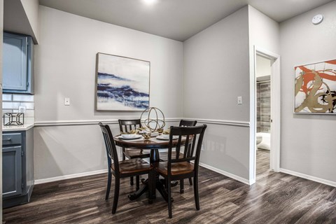 A dining room with a table set for two and a painting on the wall.