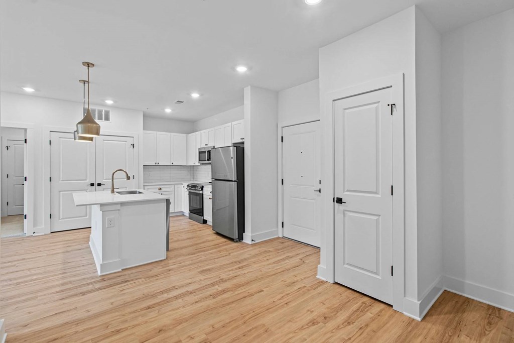 A kitchen with white cabinets and a wooden floor.
