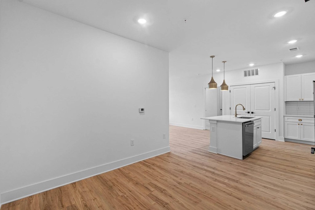 A kitchen with white cabinets and a wooden floor.