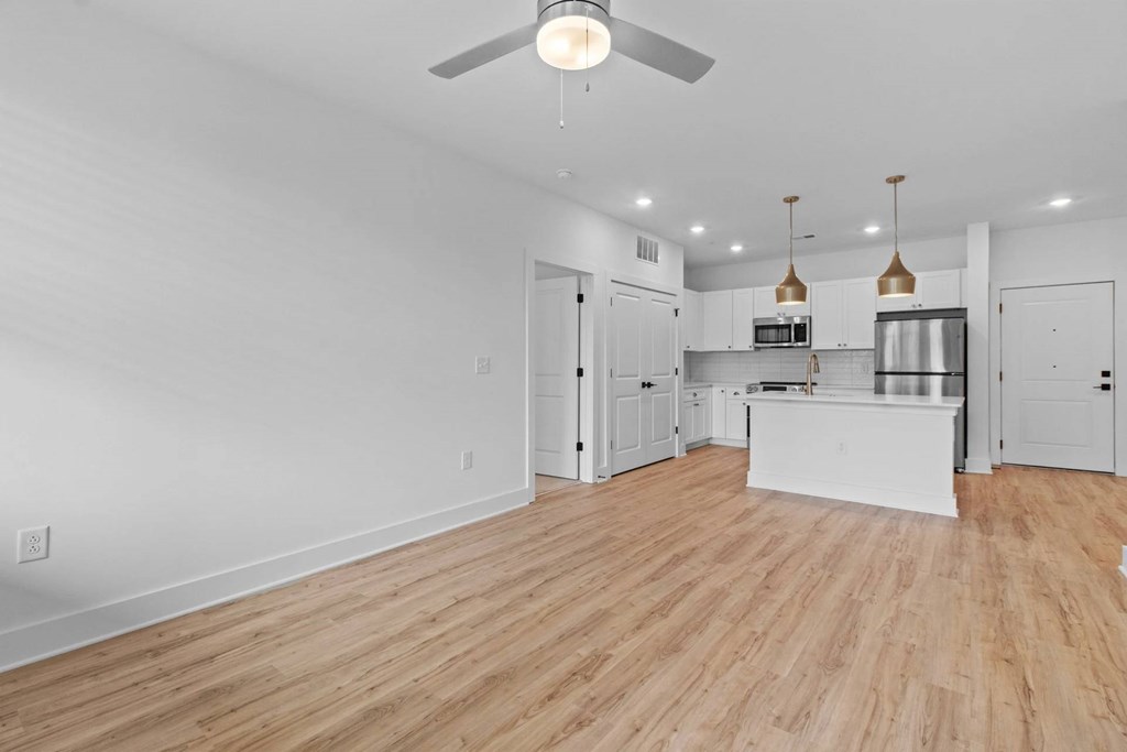 A spacious kitchen and living room with wooden floors and white walls.