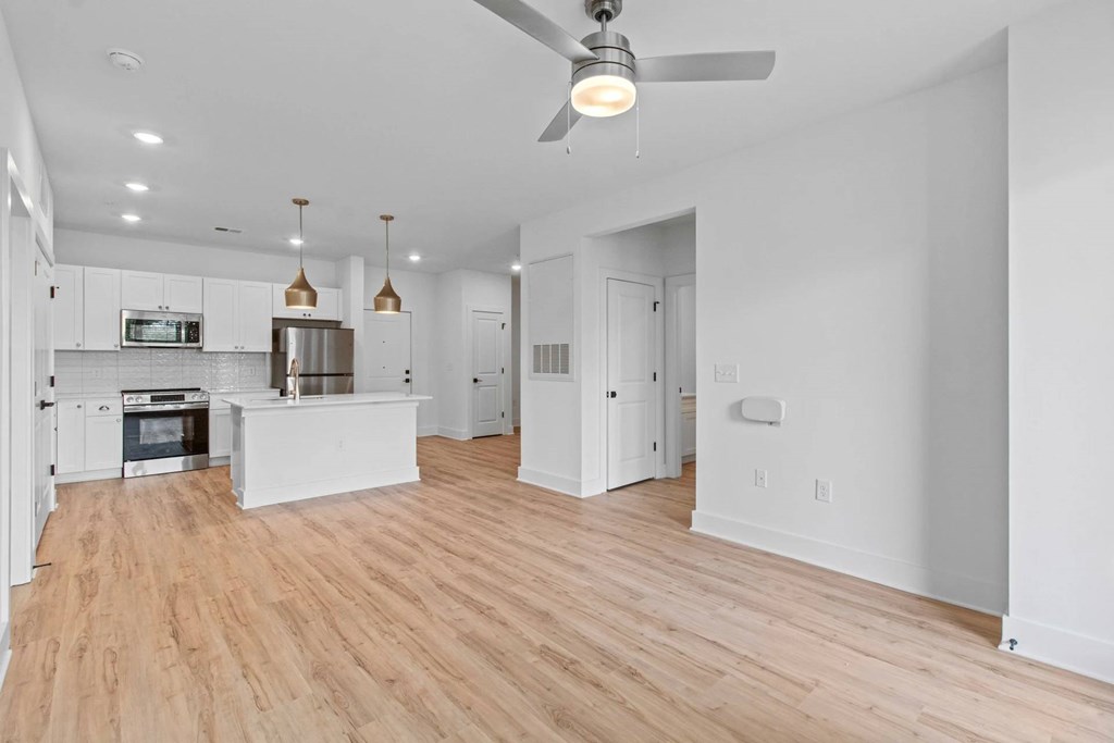 A modern kitchen with a white ceiling fan and wooden floors.