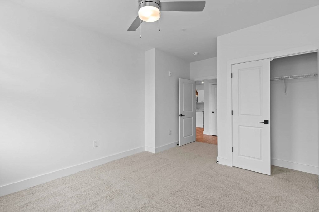 A room with a ceiling fan and carpeted floor.