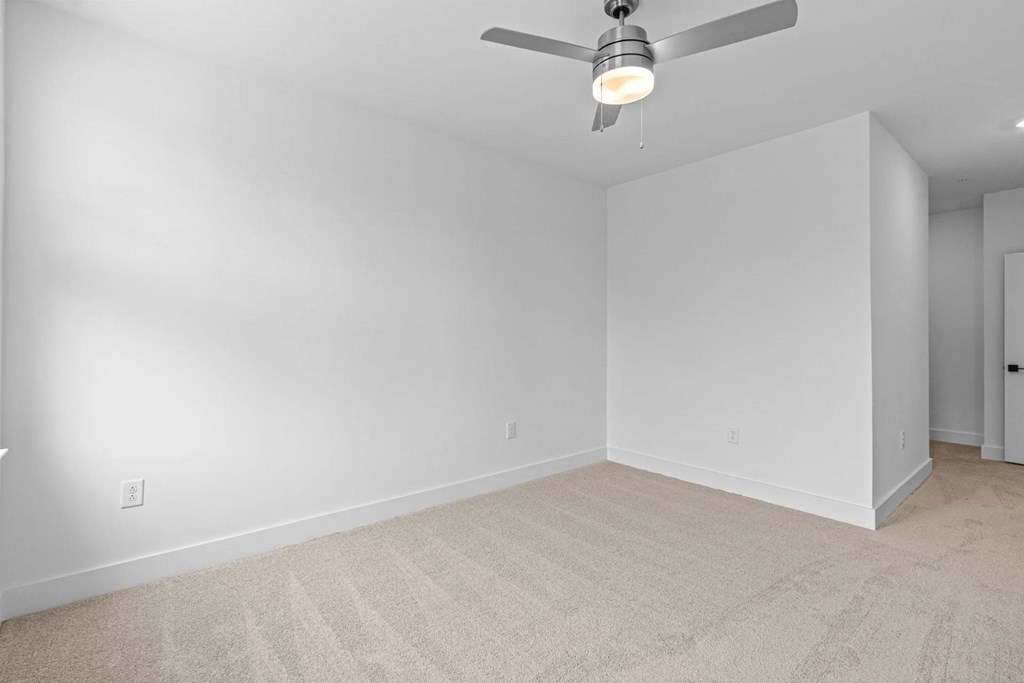 A room with a ceiling fan and carpeted floor.