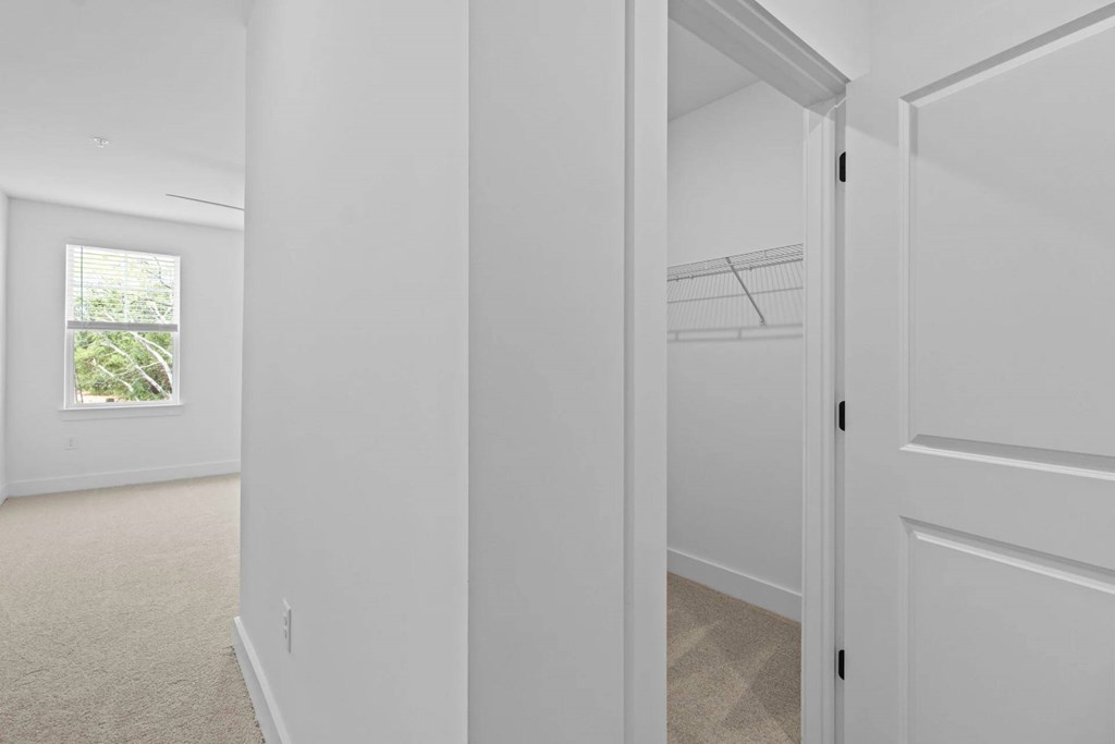 A white hallway with a door on the right and a window on the left.