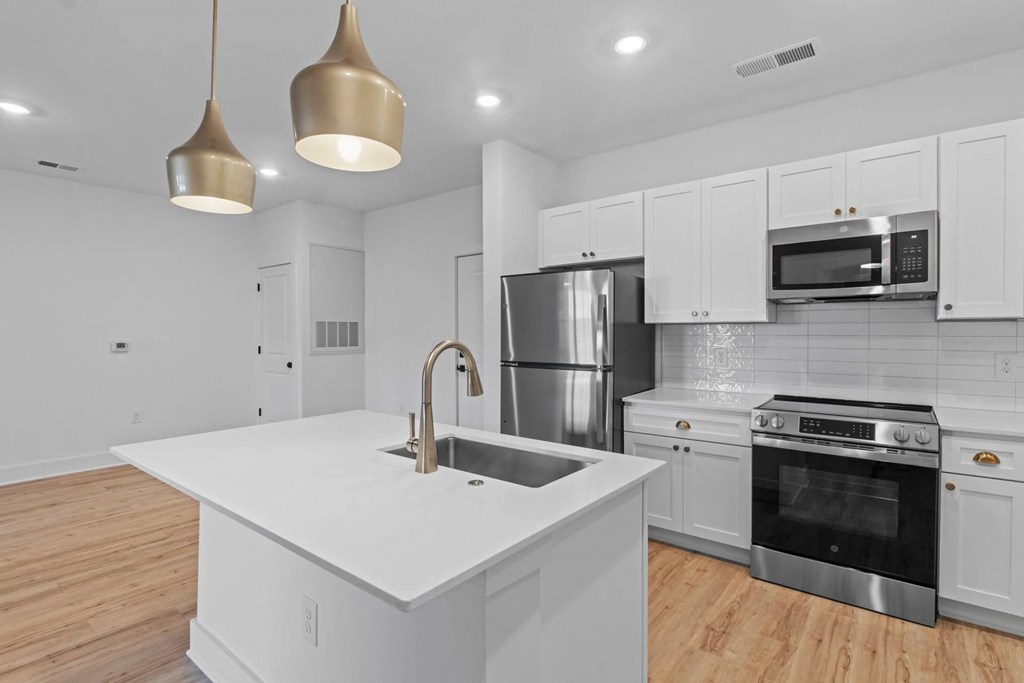 A modern kitchen with a white countertop and stainless steel appliances.