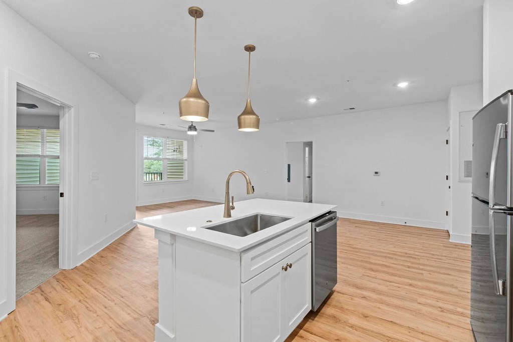 A kitchen with a white counter and wooden floors.