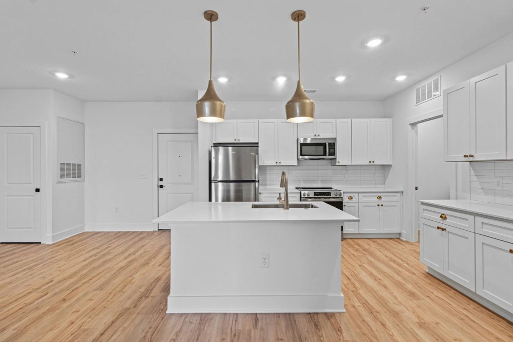 A modern kitchen with a center island and pendant lights.