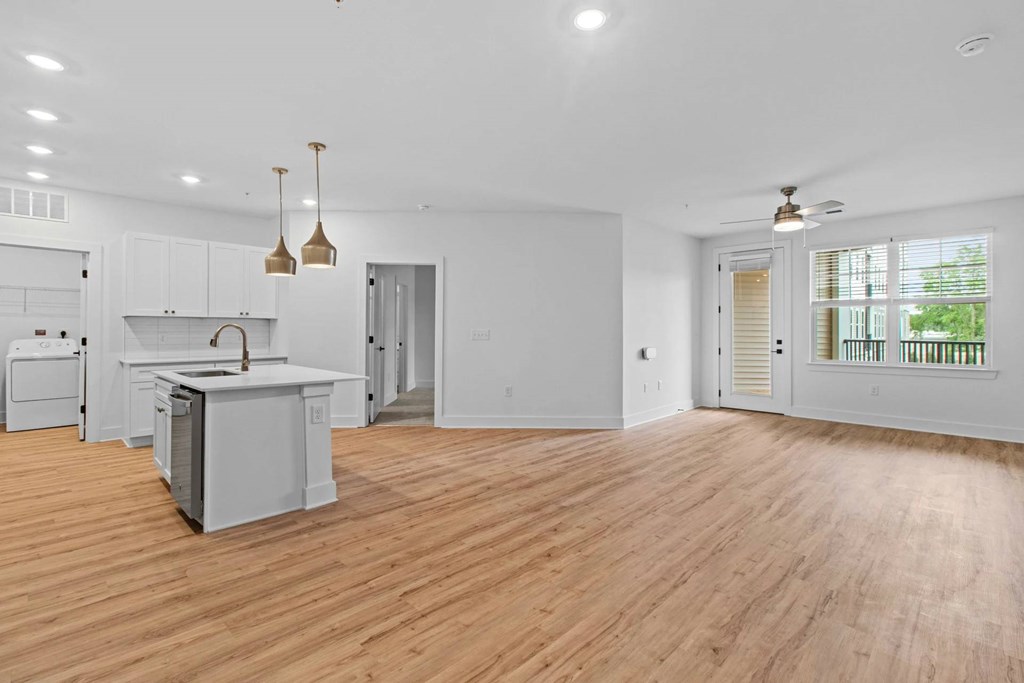 A spacious kitchen with wooden floors and white cabinetry.