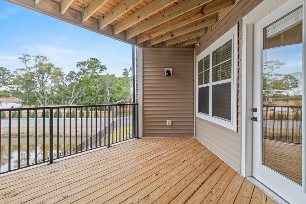 A wooden deck with a sliding glass door leading to a backyard.