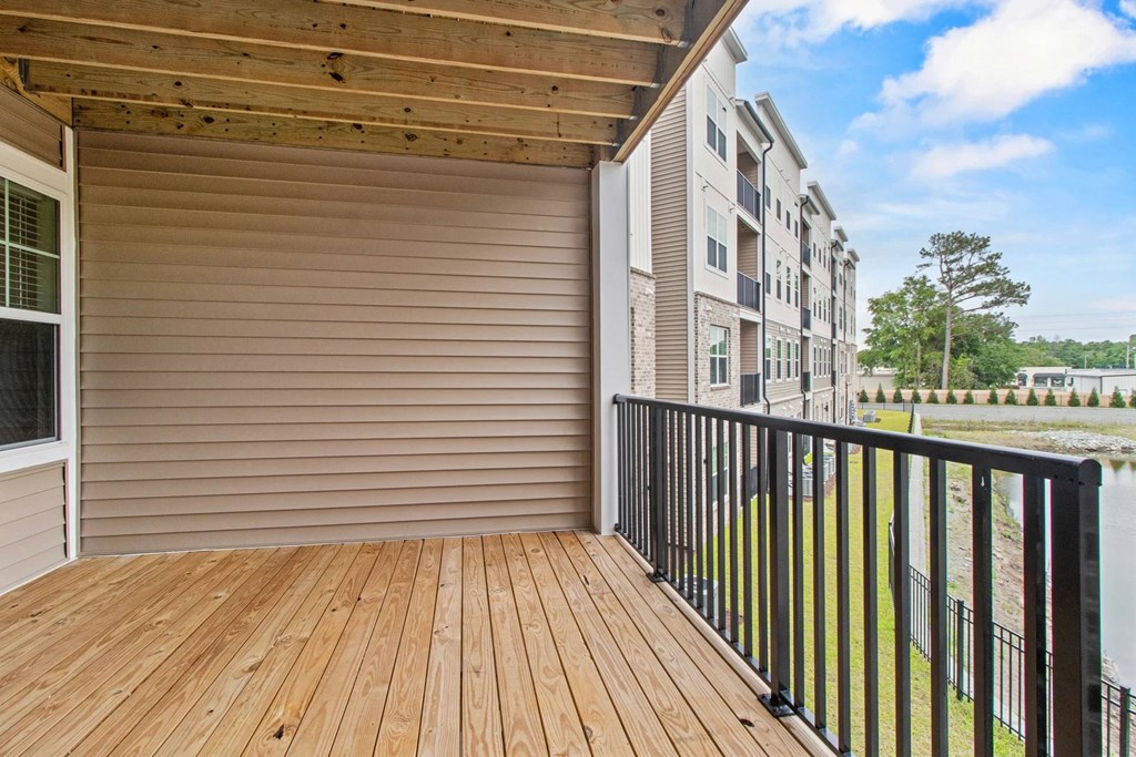 A wooden deck with a sliding door and a black railing.