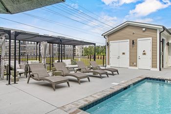 A pool area with sun loungers and a small building.