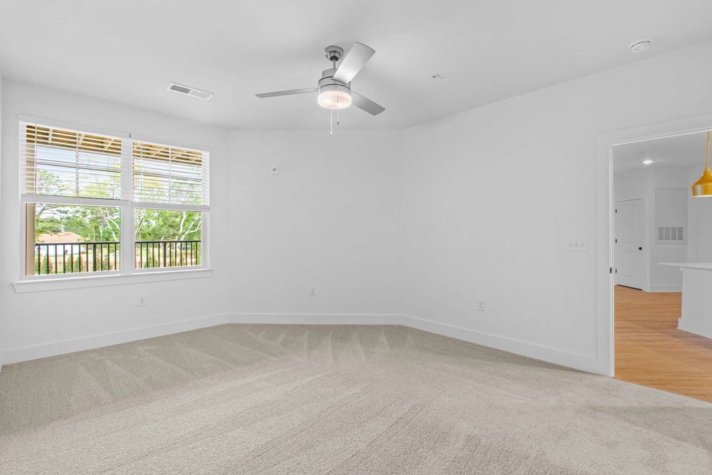 A room with a ceiling fan and carpeted floor.