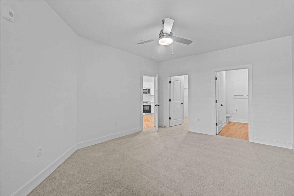 A room with a ceiling fan and carpeted floor.