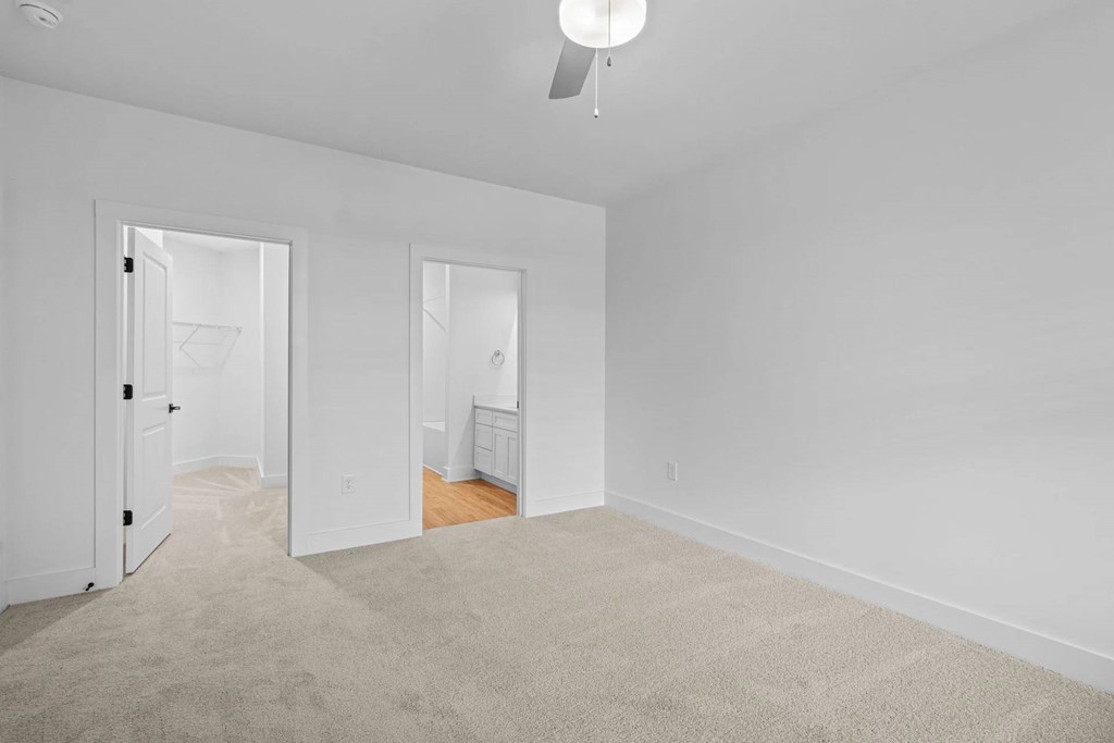 A room with a carpeted floor and two open doors.