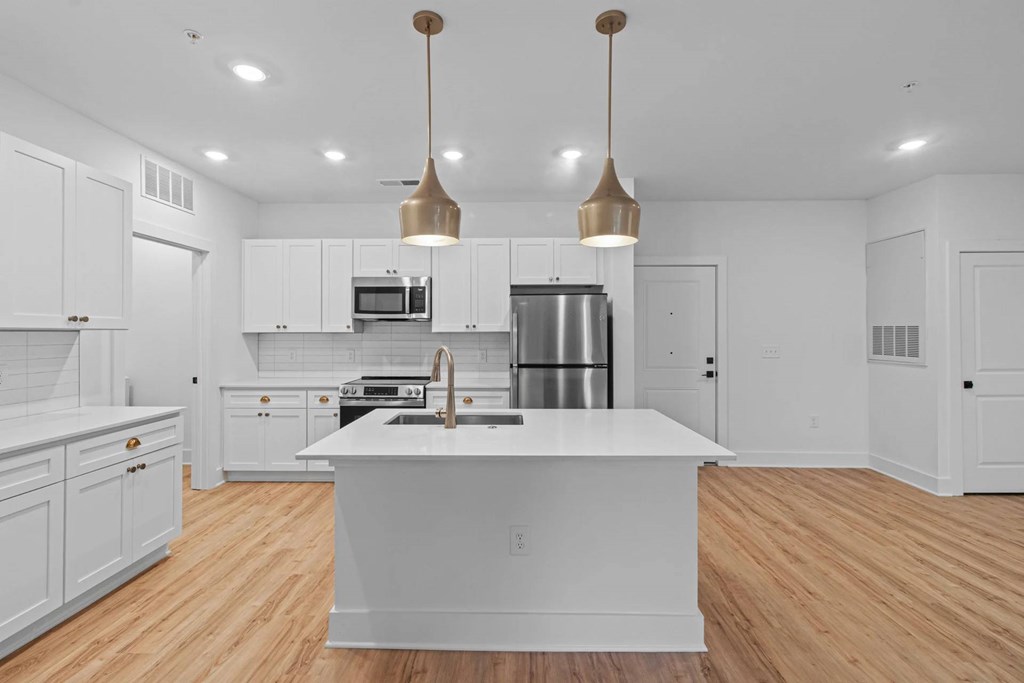 A modern kitchen with a large island and pendant lights.