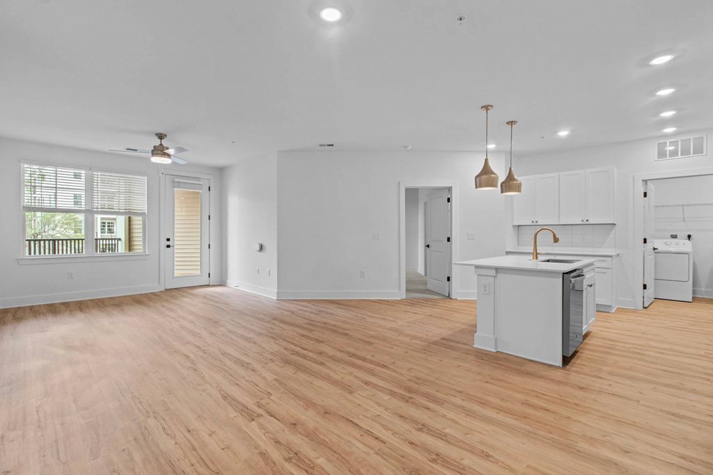 A spacious kitchen with wooden floors and white walls.
