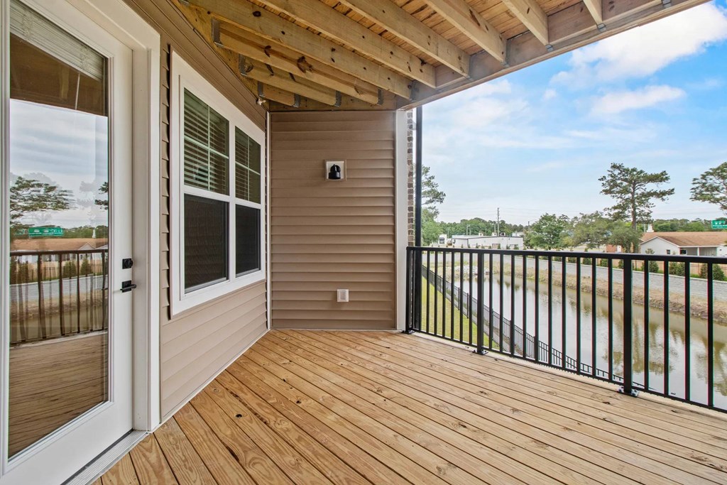A wooden deck with a black railing and a sliding glass door.