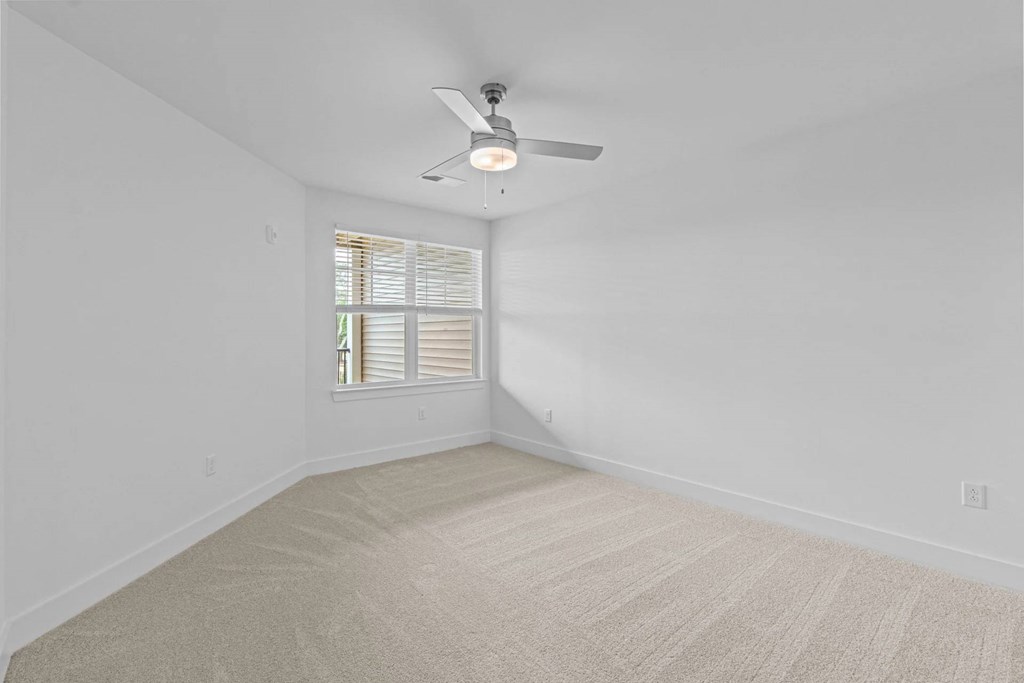 A room with a ceiling fan and a window with blinds.