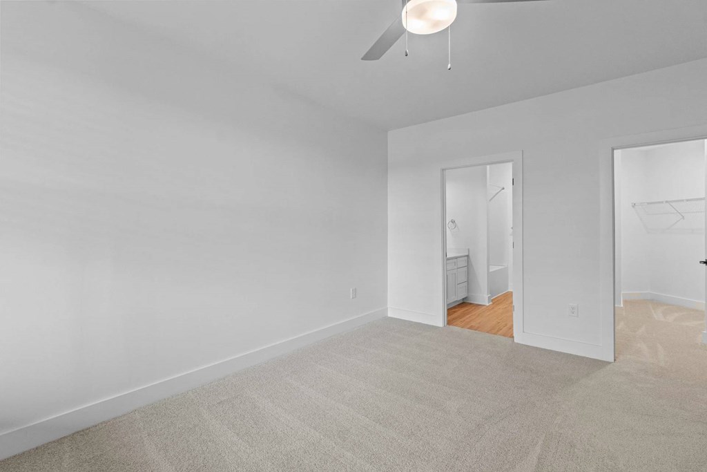 A room with a ceiling fan and carpeted floor.