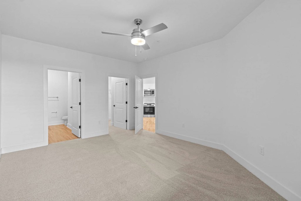 A room with a ceiling fan and carpeted floor.