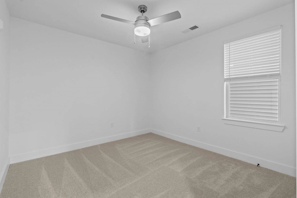 A room with a ceiling fan and carpeted floor.