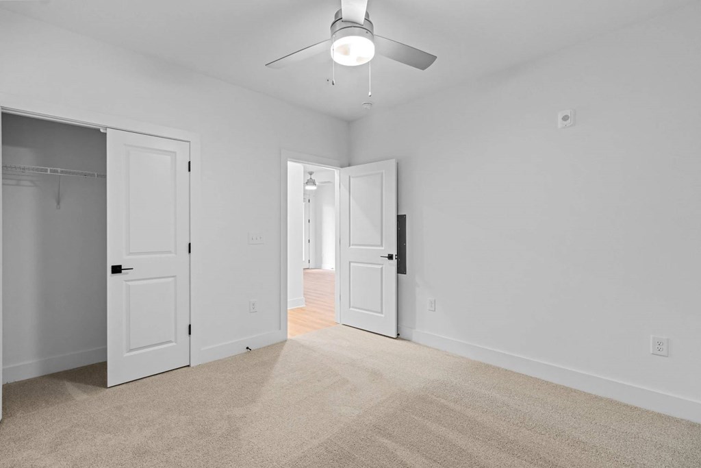 A room with a carpeted floor and a ceiling fan.