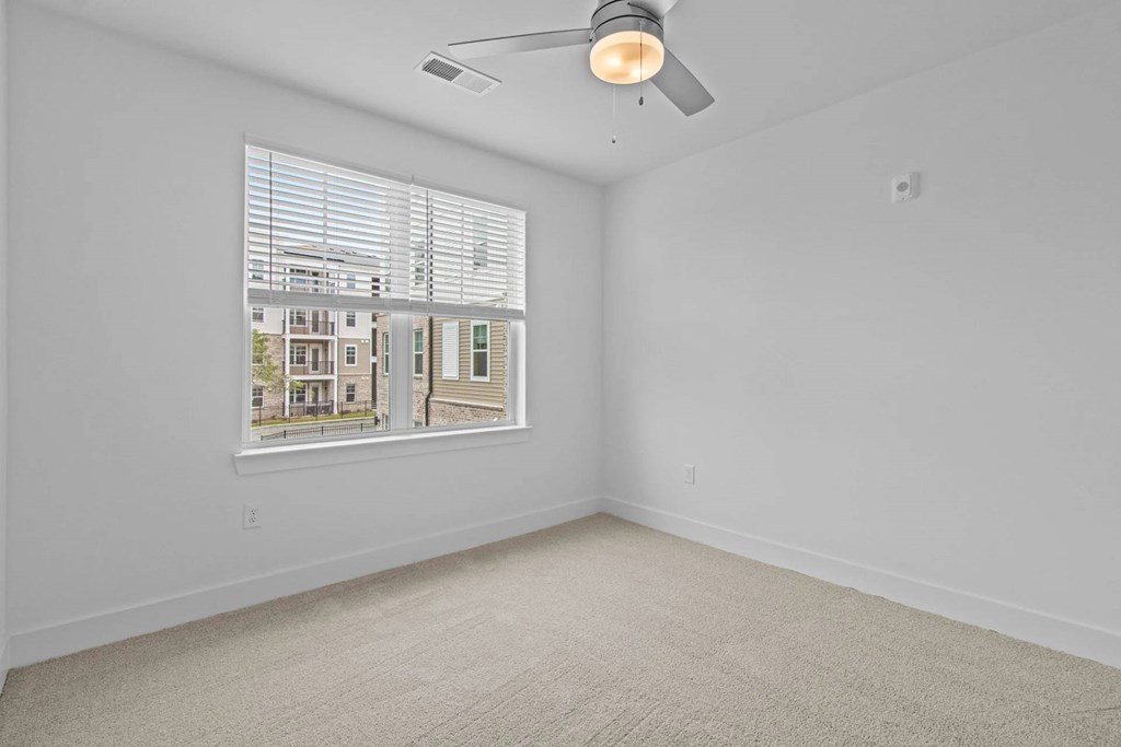 A room with a window showing a view of a residential area.