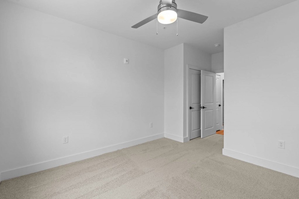 A room with a ceiling fan and carpeted floor.