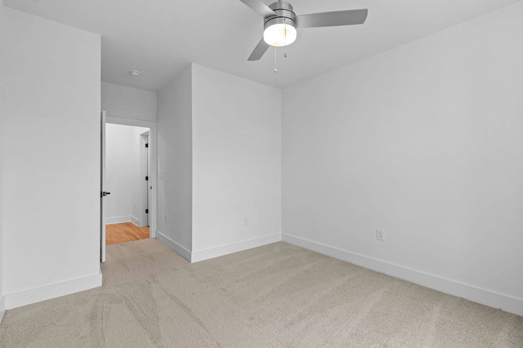 A room with a ceiling fan and carpeted floor.