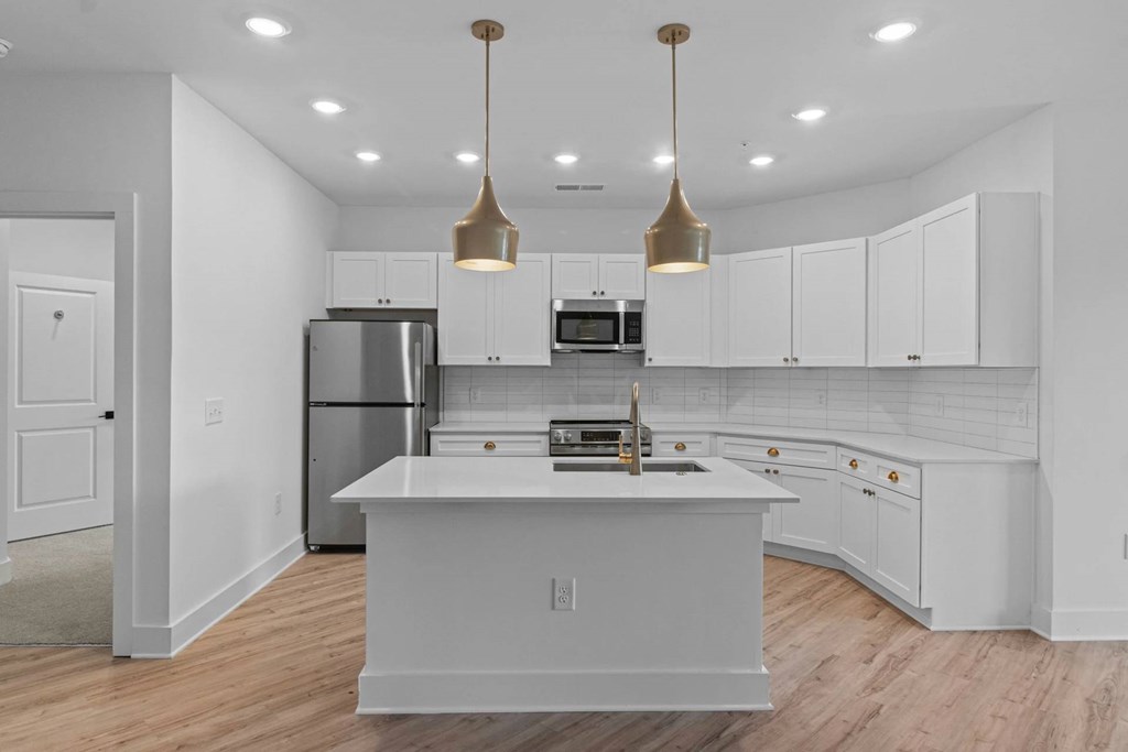 A kitchen with white cabinets and a white island.