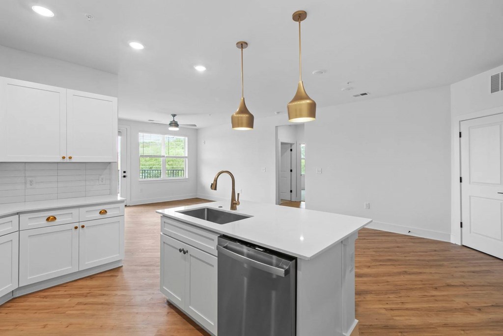 A kitchen with white cabinets and a large island with a dishwasher underneath it.