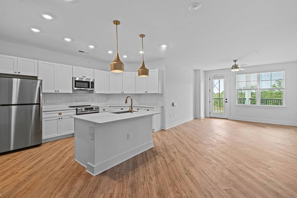 A kitchen with white cabinets and a wooden floor.