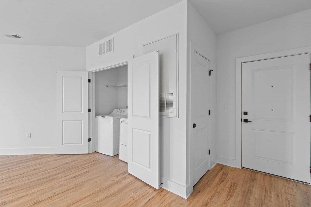 A white room with a washer and dryer in the open door.