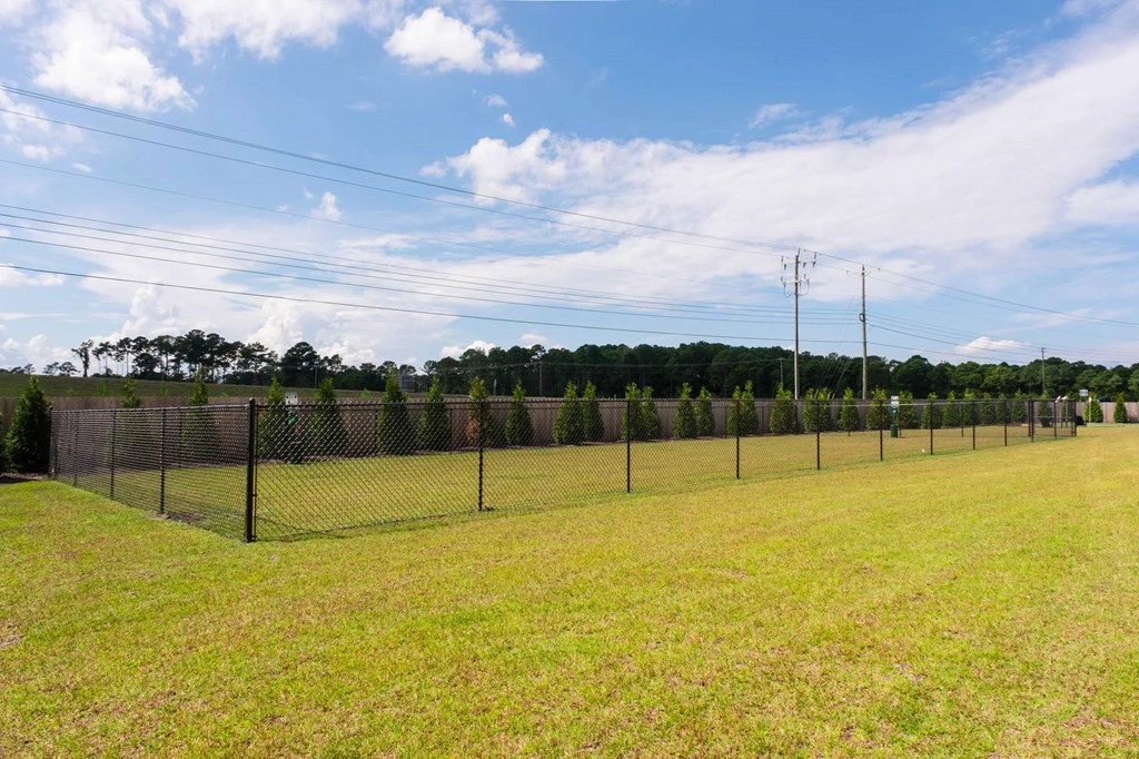 A long fence runs along a grassy field.