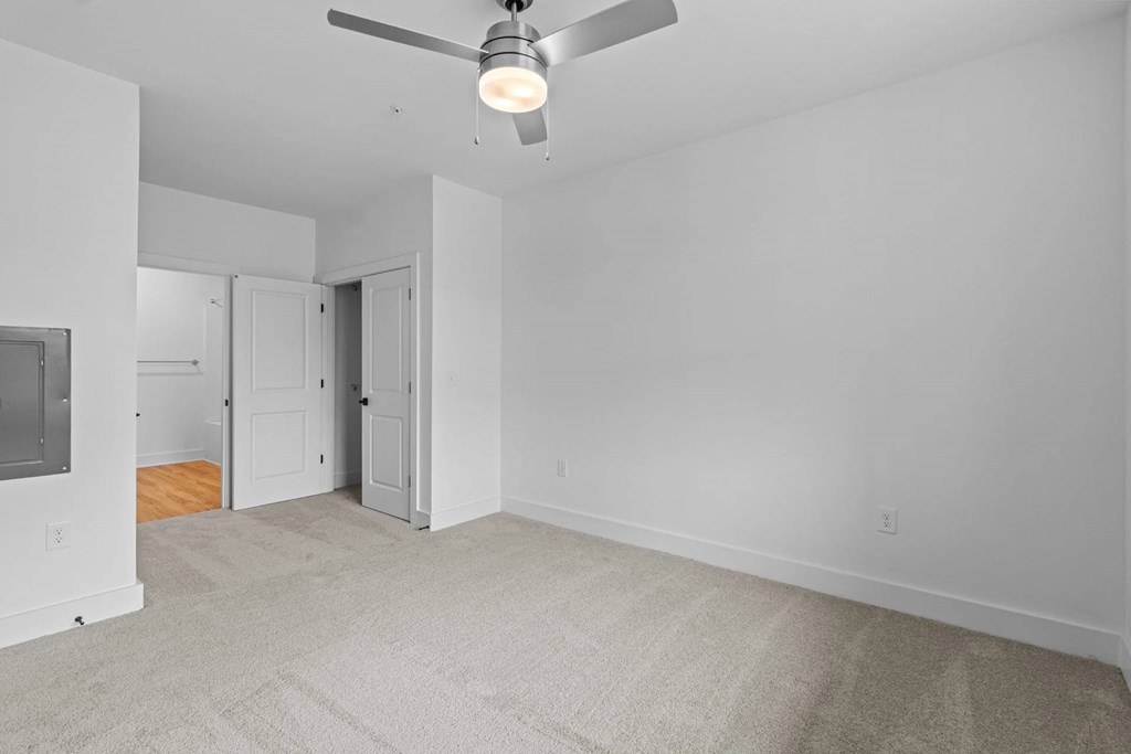 A room with a ceiling fan and carpeted floor.