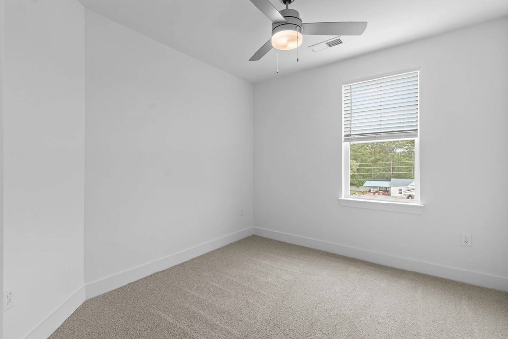 A room with a ceiling fan and a window with blinds.