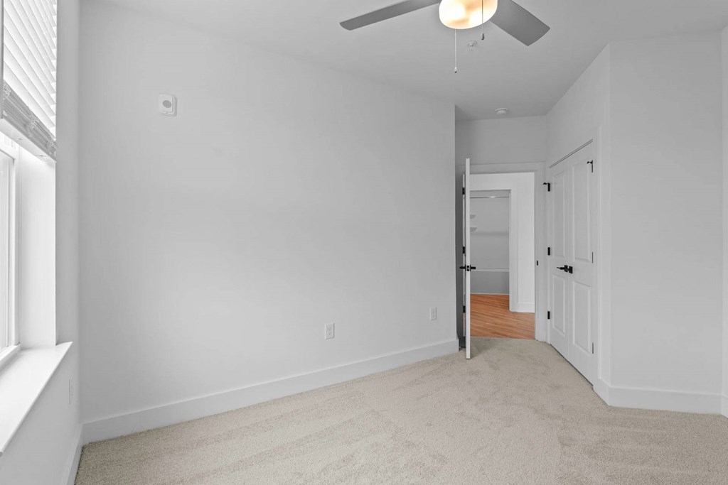 A room with a carpeted floor and a ceiling fan.