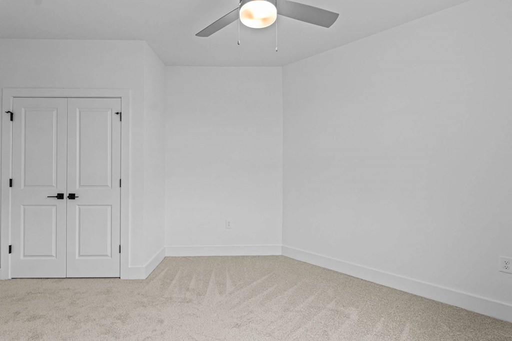 A room with a white door and a ceiling fan.