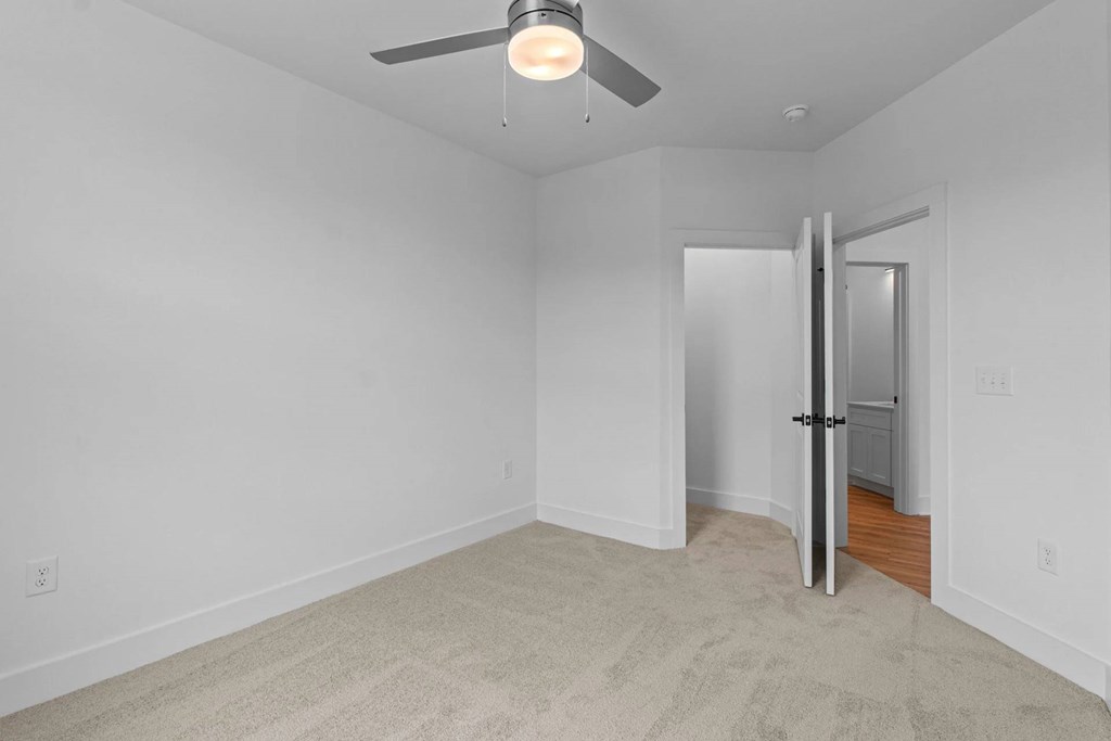 A room with a ceiling fan and a door.