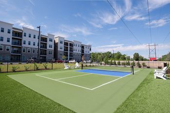 A tennis court is located in front of apartment buildings.