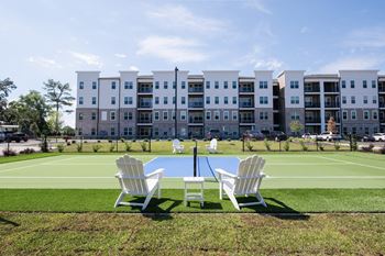 A white chair is in front of a tennis court.