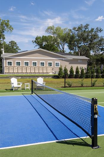 A tennis court with a blue surface and a black net.