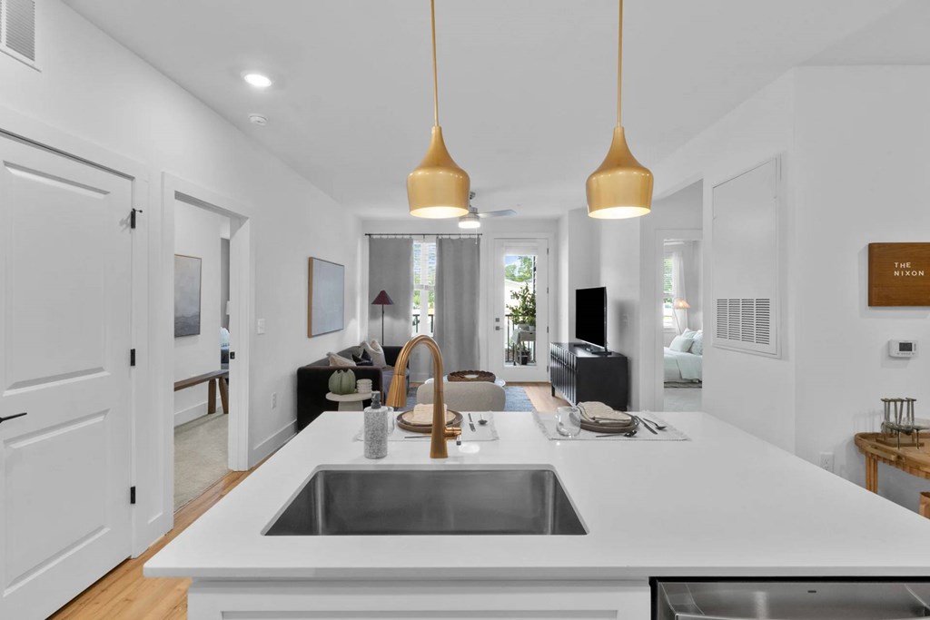 A modern kitchen with a white countertop and a stainless steel sink