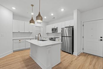A kitchen with white cabinets and a white island.