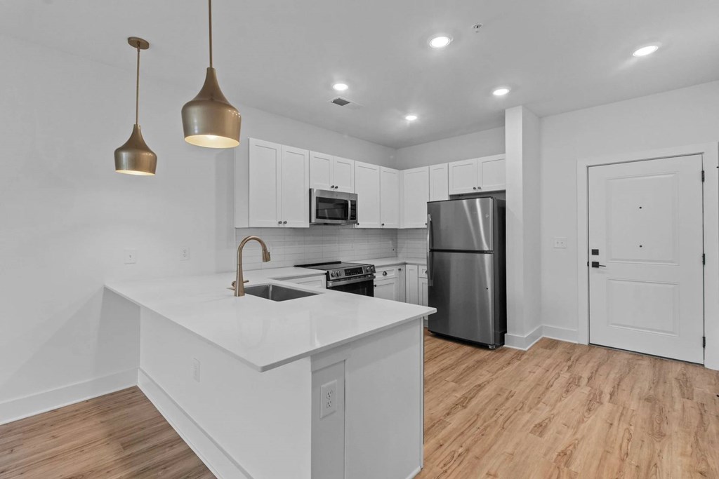 A modern kitchen with a white countertop and wooden flooring.