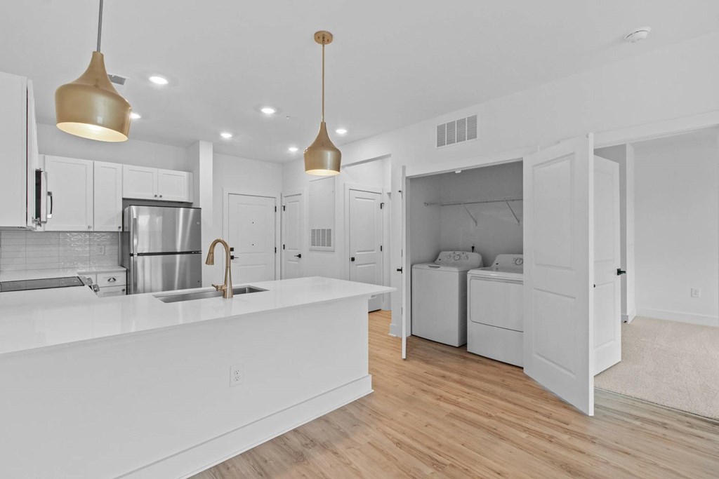 A modern kitchen with white cabinets and a wooden floor.