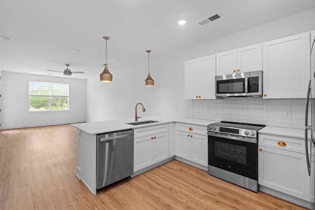 A modern kitchen with white cabinets and a wooden floor.